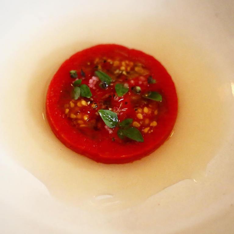 Eleven Madison Park - Birthday dinner - This is not a tomato slice, but a few delicious items visually recreating one, made with a mold and a gentle press. Tomato puree, pickled shallot, garlic croutons and tomato water.  Underneath is sheeps milk yogurt and it is garnished with basil, black pepper and olive oil - This pic is stolen from Luis’s Camera :)