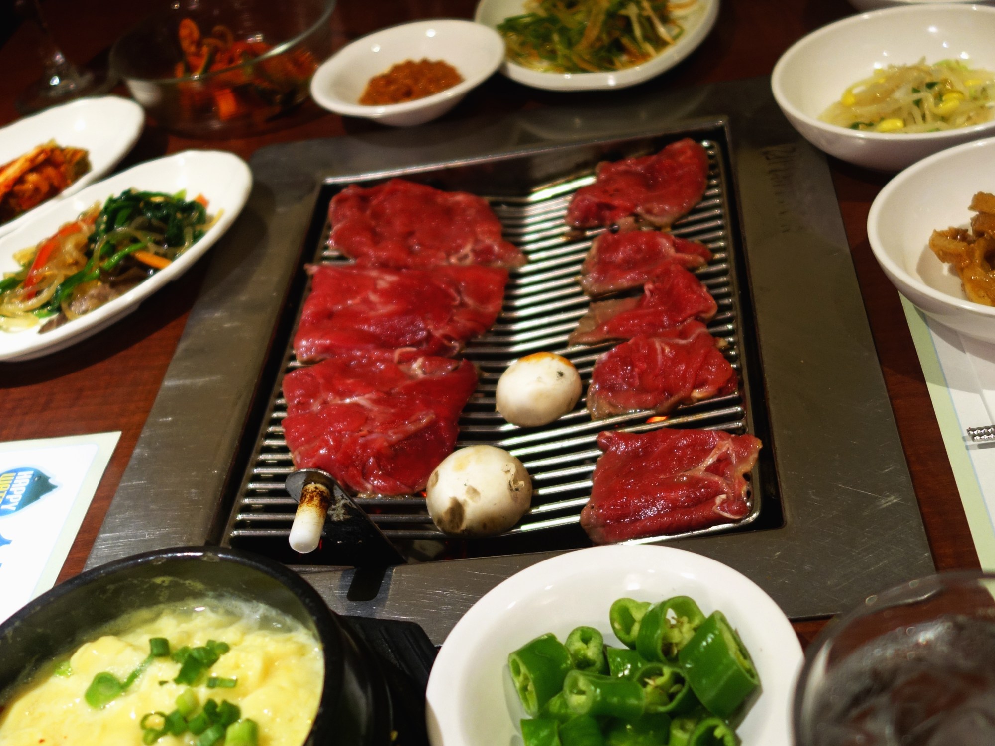 So Moon Nan Jip – Korean BBQ - Palisades Park NJ - Bulgogi just placed on the grill, all of our sides and of course my fave - steamed egg. YUM