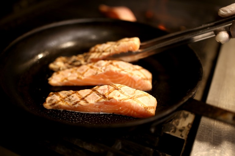 The grilled salmon is transferred to a pan, which has been sprayed lightly with pam, to bake in the oven for 13 minutes at 350 degrees.