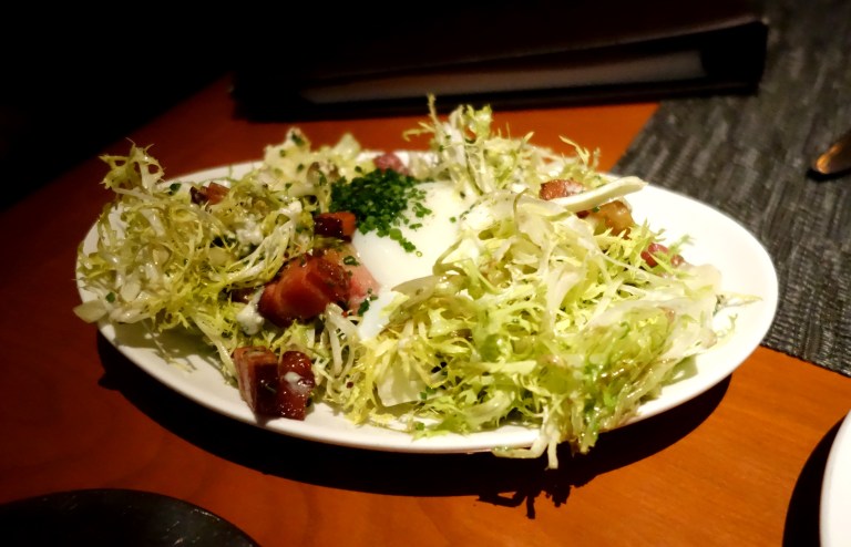Warm frisée salad topped with a poached farm egg, smoked bacon lardons and dressed in a champagne vinaigrette. YUM.